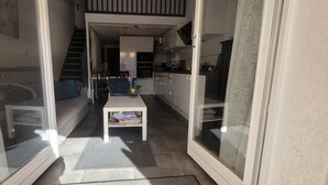 A narrow hallway with a dining area, a staircase, and a kitchen visible through glass doors. - Aux Portes du Golf, 5 mn de L'étang du Ponant, Proche de la Mer, Appartement T3 (La Grande-Motte)