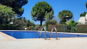 A swimming pool with metal ladders, surrounded by trees and a hedge. - Aux Portes du Golf, 5 mn de L'étang du Ponant, Proche de la Mer, Appartement T3 (La Grande-Motte)