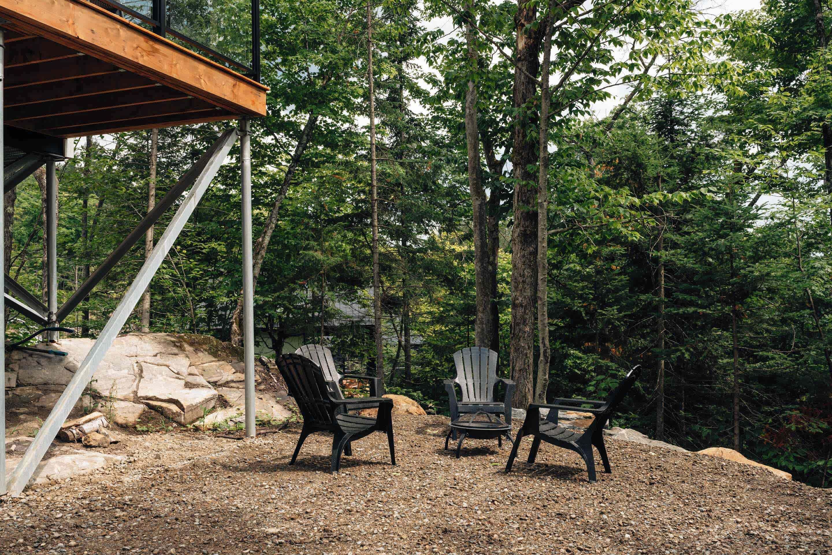 Une terrasse en bois avec des fauteuils Adirondack et un mur en pierre.