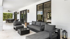 Een moderne woonkamer met een modulaire bank, een glazen salontafel en een eethoek met een tafel en stoelen.