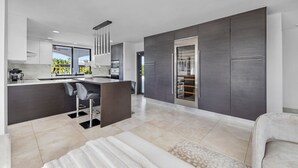 Een moderne keuken met een centraal eiland, donkere kastjes en uitzicht op de omgeving.