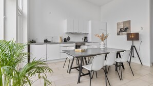 A modern kitchen with white cabinets, a dining table with chairs, and a potted plant. - 2 bedroom gorgeous home in Gilleleje (Gilleleje)