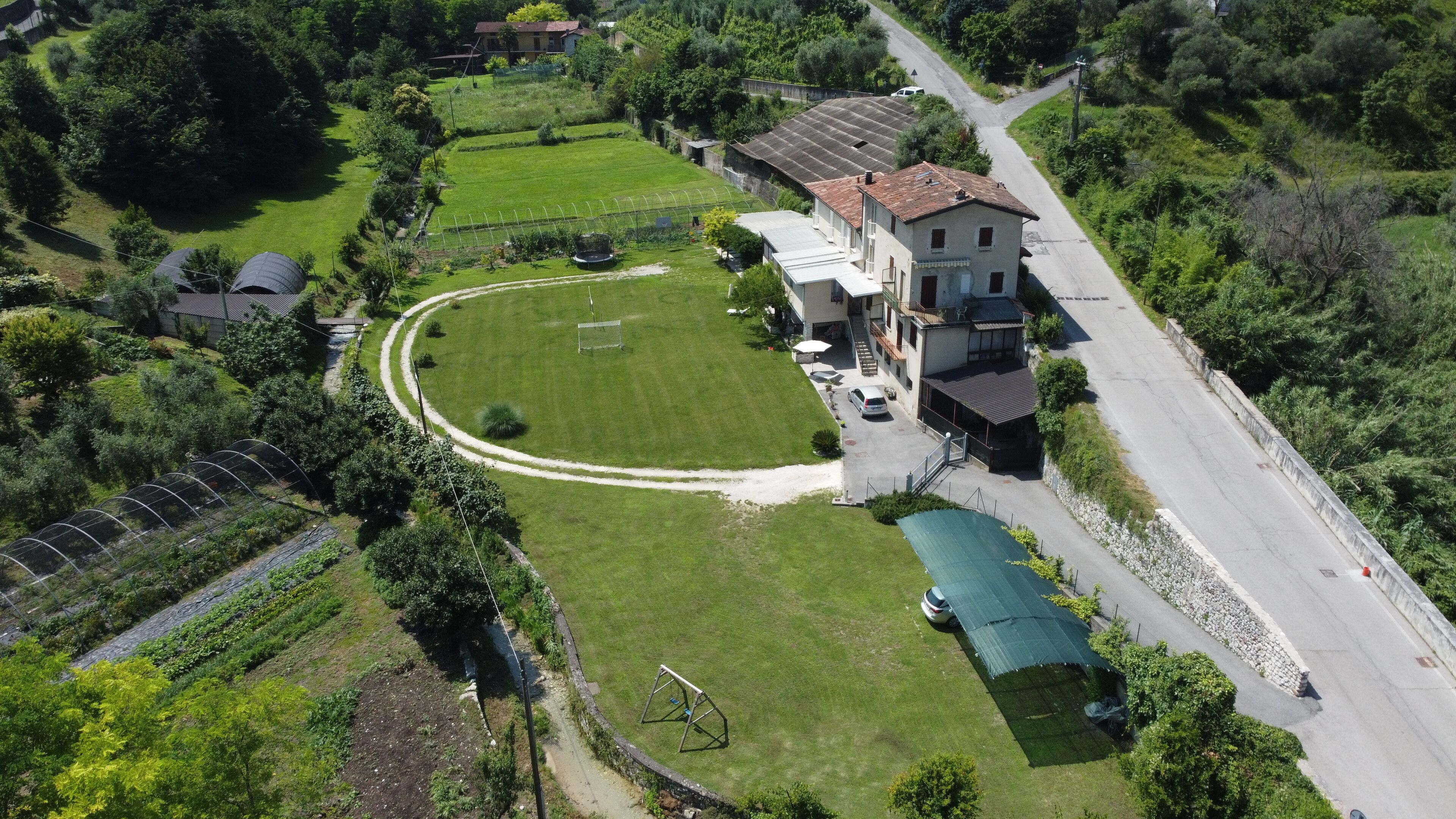 Vue aérienne d’une propriété résidentielle dotée d’une grande pelouse, d’une maison avec un toit en tuiles et d’une allée.