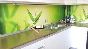 A modern kitchen with white cabinets, a stainless steel countertop, and a green bamboo-themed backsplash. - Apartment Weinduft (vine aromic) mountains beautyfull landscape (Appiano)