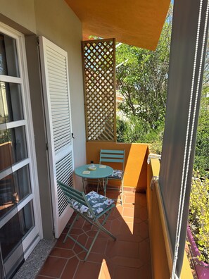 A small outdoor patio with a table and chairs, a sliding glass door, and a wooden lattice partition. - A welcoming B&B for families and couples. Ample free parking is available. (Santa Giusta)