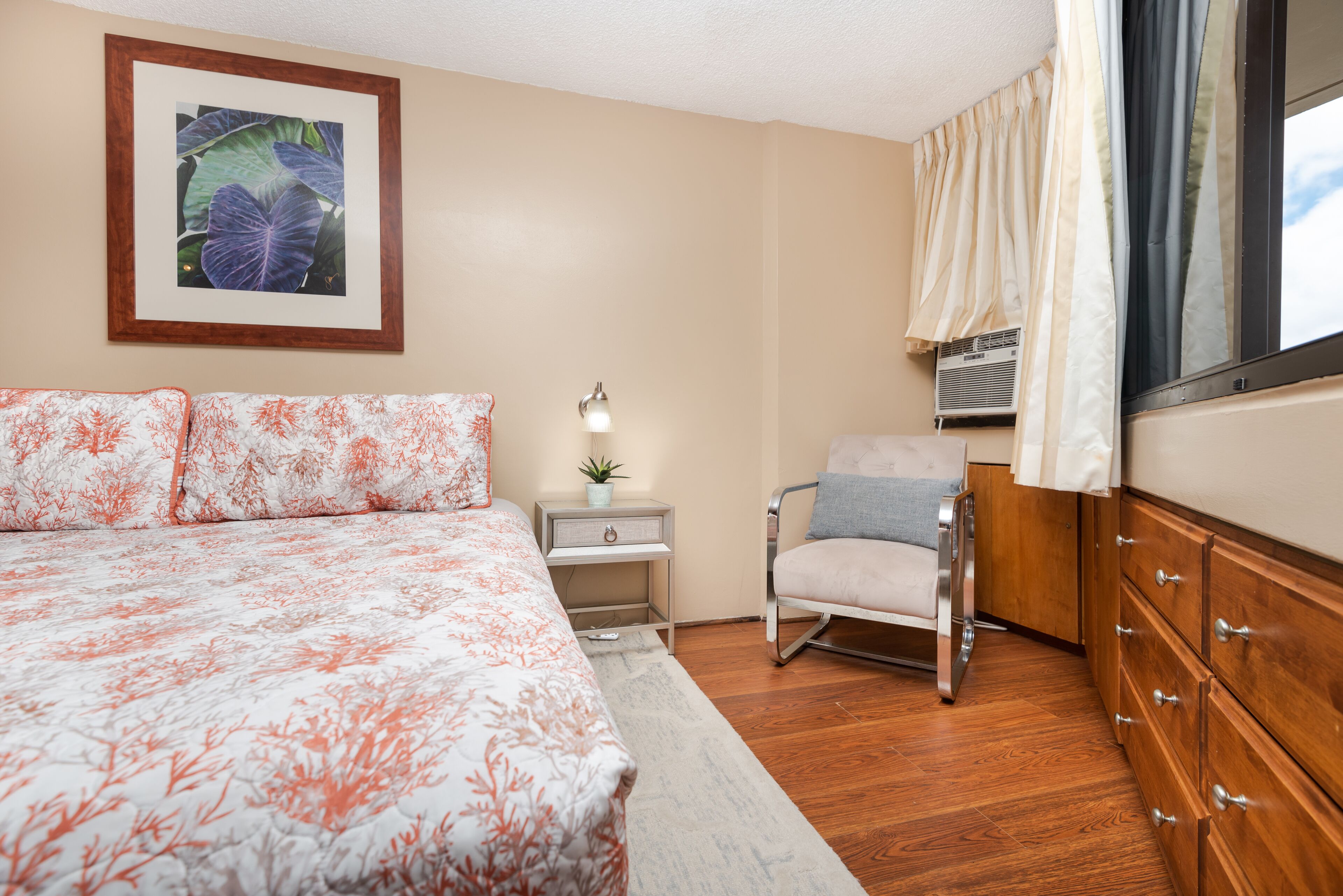 Une chambre à coucher avec un grand lit, une table de chevet avec une lampe, une chaise et une commode.