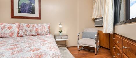 Une chambre à coucher avec un grand lit, une table de chevet avec une lampe, une chaise et une commode.