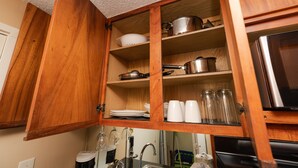 A wooden kitchen cabinet with shelves holding dishes, pots, and glass jars. - Free Parking! 40th Floor Penthouse Studio with Stunning View (Honolulu)