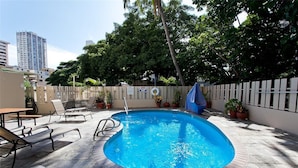 A swimming pool with a tiled deck, lounge chairs, and potted plants. - Studio in the Middle of Waikiki, Short walk to beach (Honolulu)