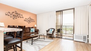 Un soggiorno moderno con zona pranzo, divano, pannello decorativo e vista attraverso una porta scorrevole in vetro.