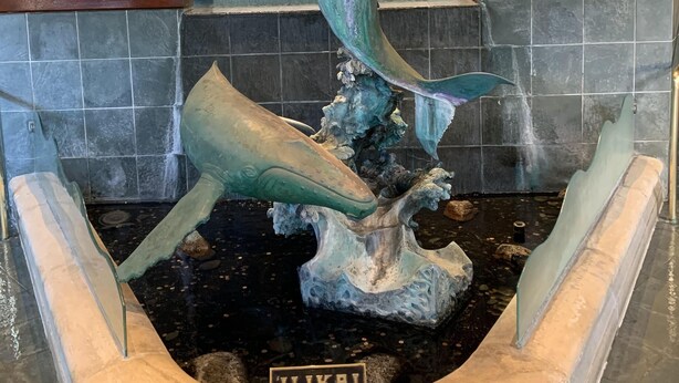 Una escultura de ballena en un vestíbulo con una placa que dice "ILIKAI" y una cita.