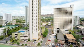 Un edificio alto con varios pisos, rodeado de otros edificios y vegetación.