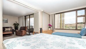 Habitación de hotel con una cama grande, un sofá, una silla, un escritorio y vistas a un edificio a través de la ventana.