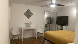 Ett sovrum med en säng, ett skrivbord, två stolar, en tv och en garderob.