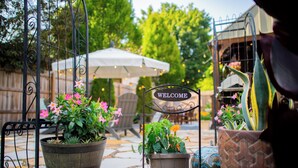 Un letrero de bienvenida, plantas en macetas y un patio con suelo de piedra.