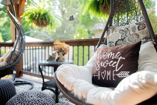 A wicker chair with a cushion that reads "home sweet home" and a small table with a vase of flowers. - The Dryer House - A Charming Restored Home in a Walkable Neighborhood (Springfield)