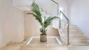 A modern staircase with a glass railing and a potted plant on a platform.