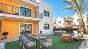 A two-story building with a balcony, outdoor seating, and a hot tub.