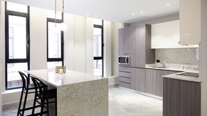 Een moderne keuken met een groot eiland, inbouwapparatuur en grote ramen.