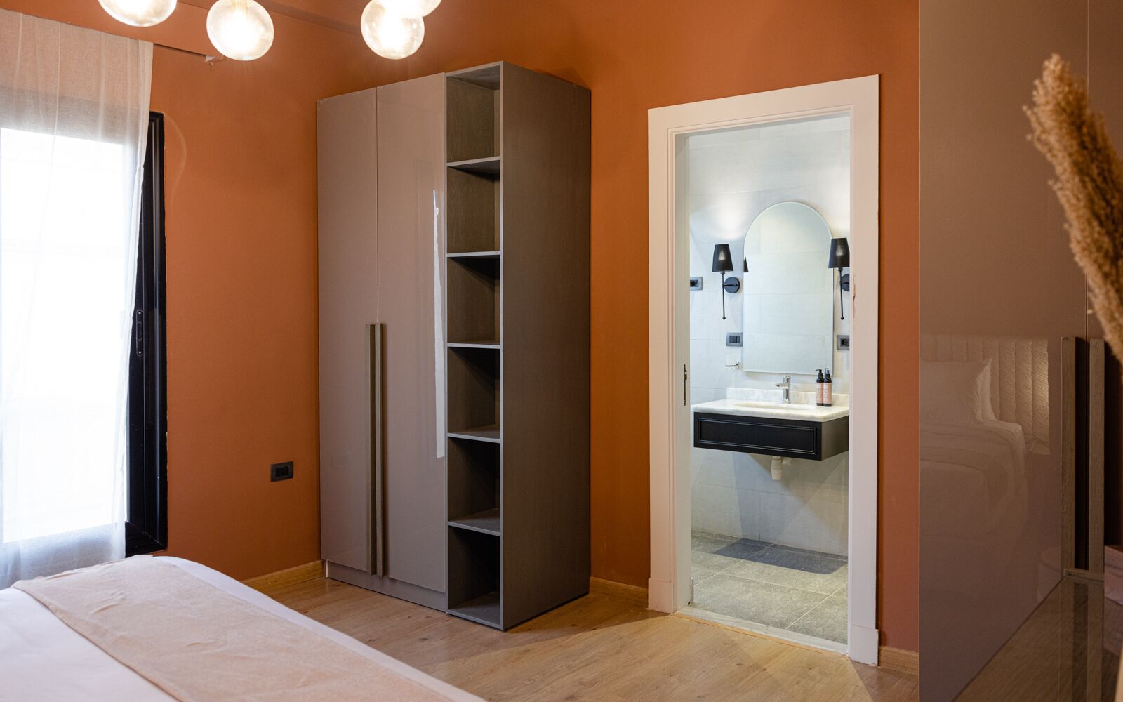 Une chambre à coucher comprenant un lit, une armoire et une salle de bain avec un lavabo et un miroir.