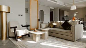 Een moderne woonkamer met een bank, fauteuils, een salontafel en een lamp.
