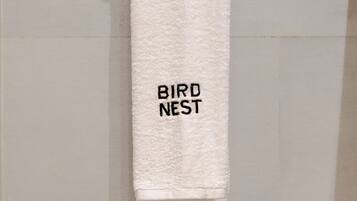 A white towel hanging on a metal towel rack in a bathroom with plain tiled walls.