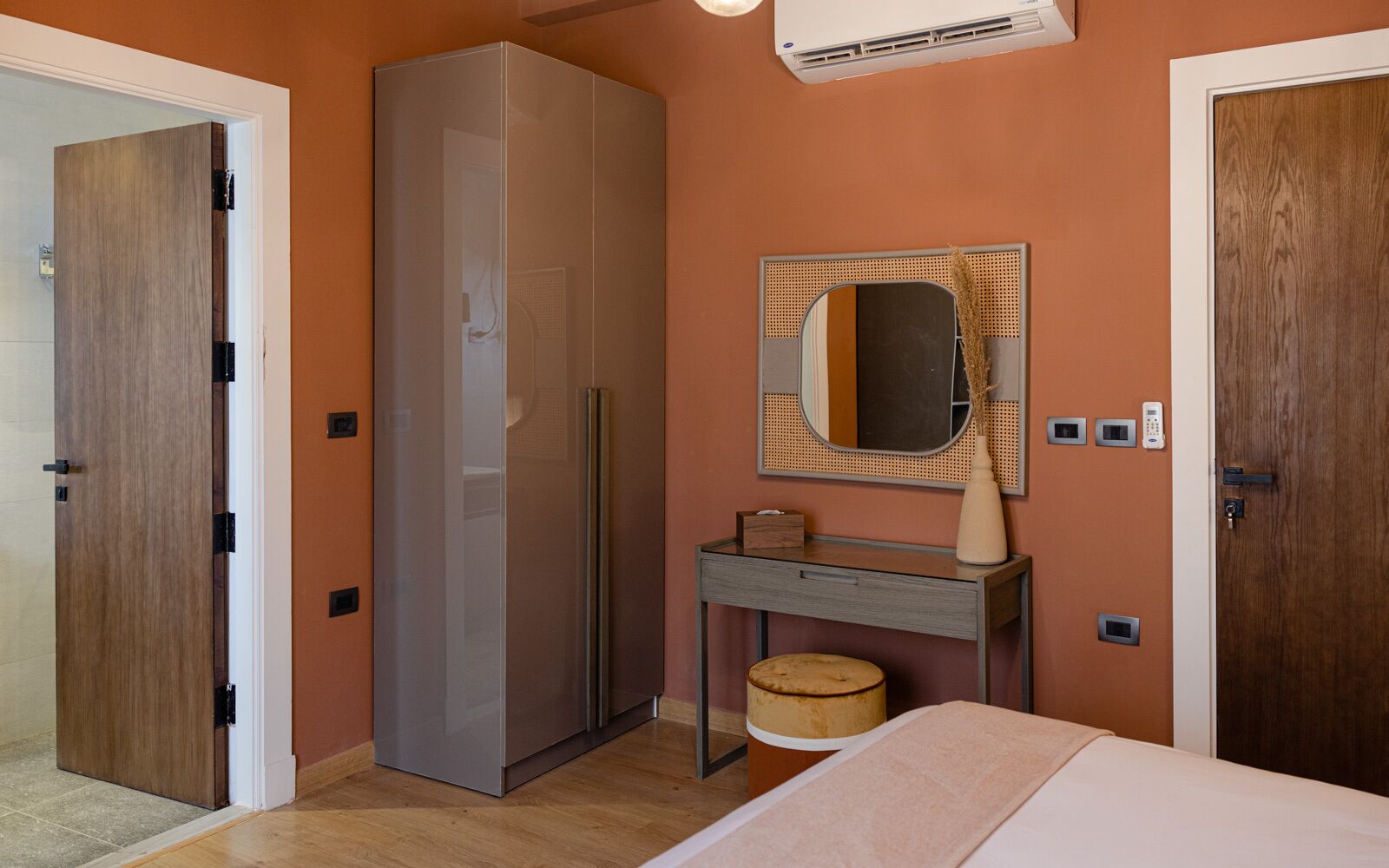 Un dormitorio con armario, tocador con espejo, mesita de noche y cama.