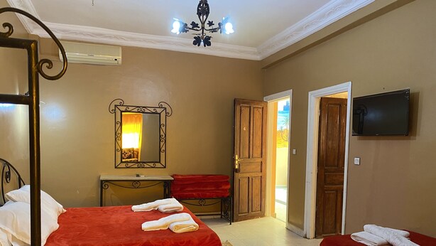 A hotel room with two beds, a mirror, a television, and a door leading to another room.