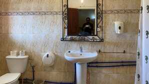 A bathroom with a toilet, sink, and mirror.