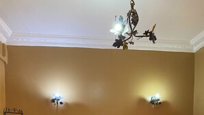 A neatly made bed with white linens, a dark patterned bedspread, and two wall-mounted lamps.