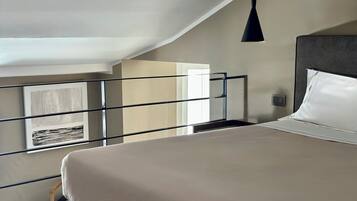 A bedroom with a bed, a hanging light fixture, a window with a view, and a door.