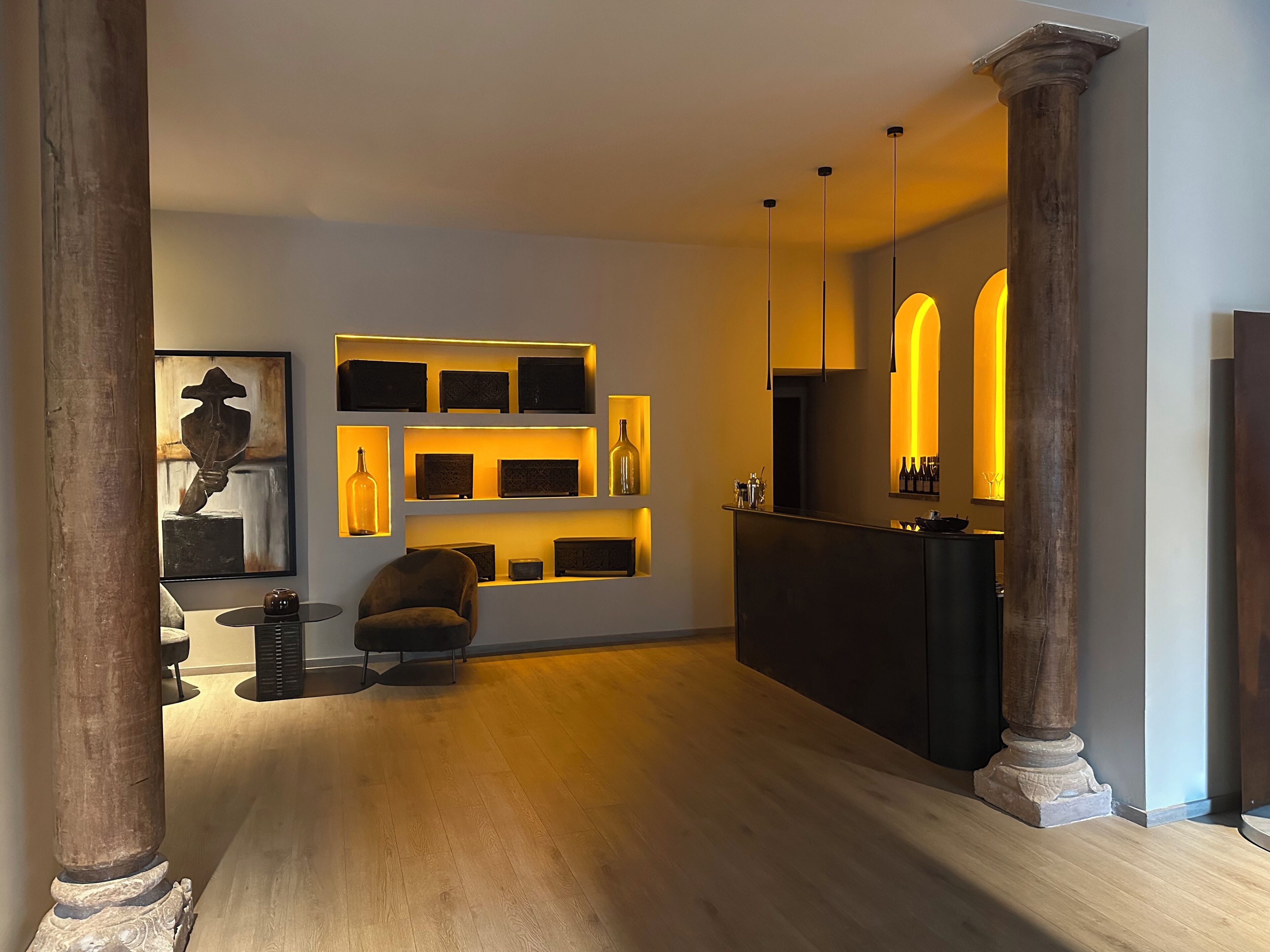 Un interior moderno con suelo de madera, una recepción y una estantería con objetos decorativos.