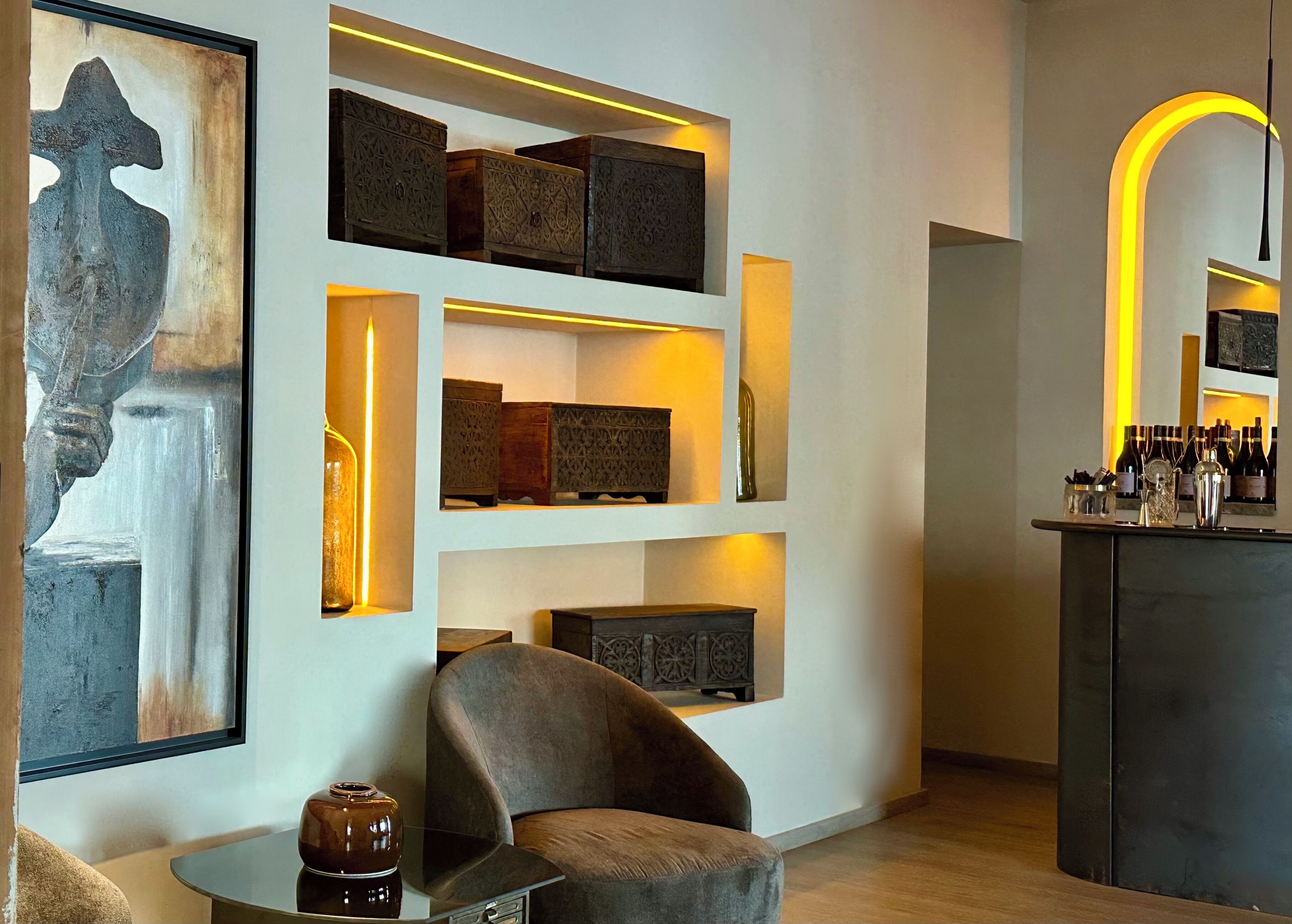 A modern interior with a sofa, a coffee table, and a bar area with bottles.