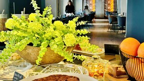 A dining area with a table set for a meal, including a chocolate dessert, a bowl of oranges, and a potted plant. - Palazzo Liberty (Palermo)