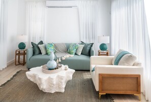 Sala de estar com sofá, poltrona, mesa de centro e luminárias.