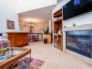 A spacious living room with a fireplace, a dining area, and a kitchen.