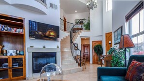 A spacious living room with a fireplace, a staircase, and a large window. - Condo 40-4 El Dorado Ranch (San Felipe)