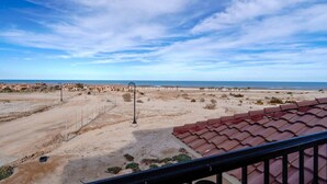 A coastal view with a sandy beach, a clear sky, and a residential area with buildings and a street lamp. - Condo 40-4 El Dorado Ranch (San Felipe)
