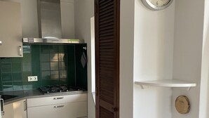 Une cuisine moderne avec une cuisinière à gaz, des armoires blanches et une horloge au mur.