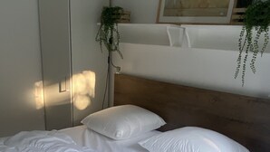 Un lit bien fait, avec du linge de lit blanc, dans une chambre dont la tête de lit est en bois.