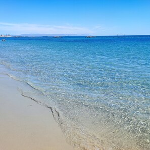Ein Strand mit klarem Wasser und sandigem Ufer.