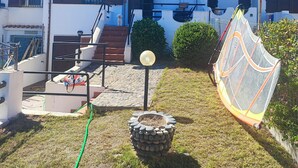 A two-story building with a staircase leading to the entrance, a small garden area with a stone planter, and a metal fence. - Villa 100 steps from the beach (CIN It092066C2000R5478) (Sardegna)