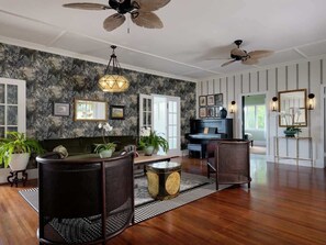 A spacious living room with a piano, a dining area with wicker chairs, and a large window.