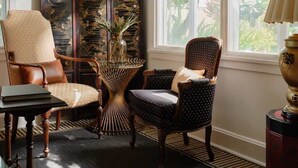 A room with a large window, two chairs, a sideboard, and a decorative panel. - Kahili Suite - Historic charm meets Luxury (Wailuku)