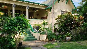 A two-story house with a green roof, a covered porch, and a stone pathway leading to the entrance.