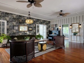 A spacious living room with a piano, wicker furniture, and a large mirror.