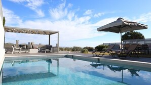 Een helderblauw zwembad met ligbedden en parasols, omringd door een pergola en tuinmeubilair.