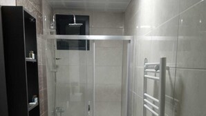A modern bathroom with a glass-enclosed shower, a toilet, a sink, and a towel rack.