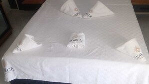 A hotel room with a bed, pillows, and towels with the brand 'AKARCA' visible.
