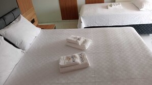 A hotel room with two beds, each with white linens and a folded towel with the hotel name.